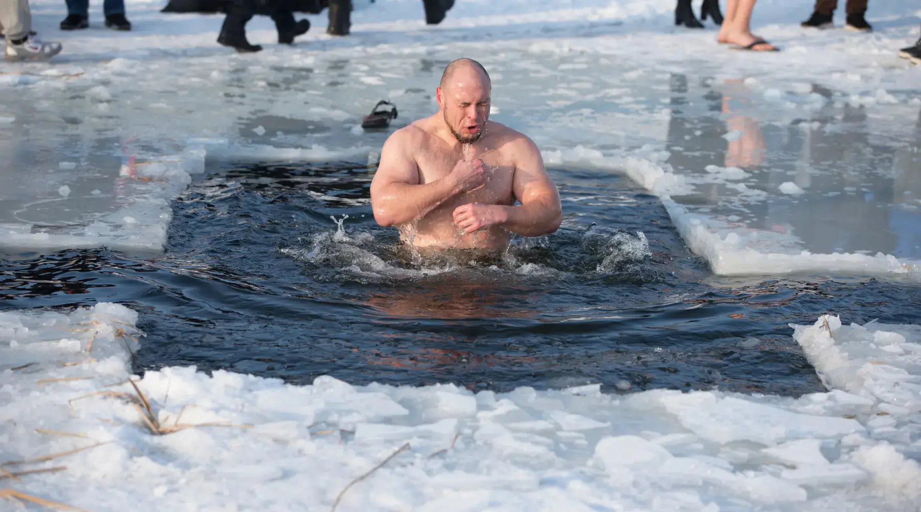 A man practicing cold plunging emerging from ice lake